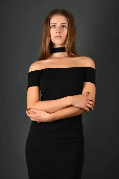 Young brunette lady in black dress posing on grey background