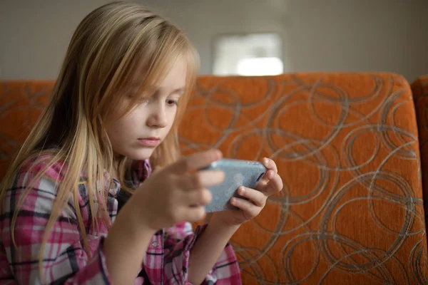 Little child girl play on smartphone at home. Cell phone addiction.