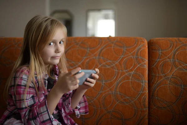 Little child girl play on smartphone at home. Cell phone addiction.