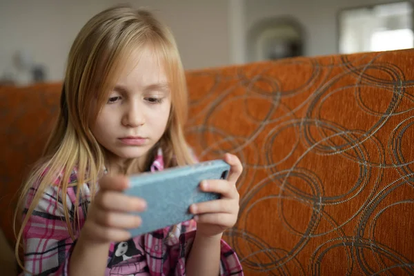 Little child girl play on smartphone at home. Cell phone addiction.