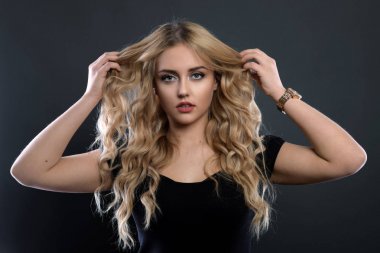 Sarışın kız parlak dalgalı saçlı uzun ve hacim. Güzel bir kadın modeli kıvırcık saç modeli ile .