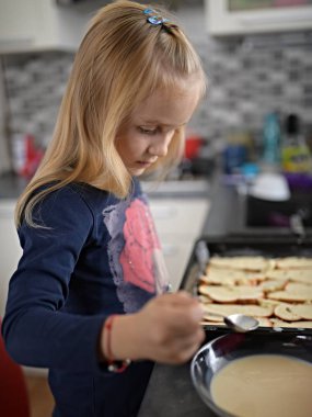 Sevimli küçük kız mutfakta yemek hazırlarken eğleniyor. 