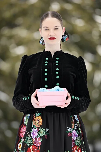 冬の肖像画の美しいSlovak女性で伝統的なドレスで色イースターの卵 — ストック写真