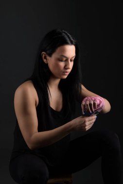 Boks yapıyorum. Kadın boksör bankta oturuyor. Bandajı yakın plan çekime sokuyor. 