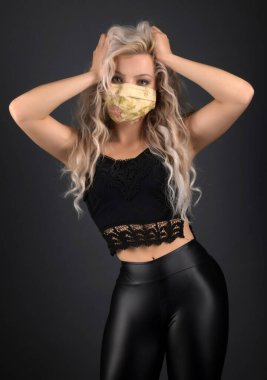 Uzun kıvırcık saçlı, solunum maskeli güzel sarışın kadın.