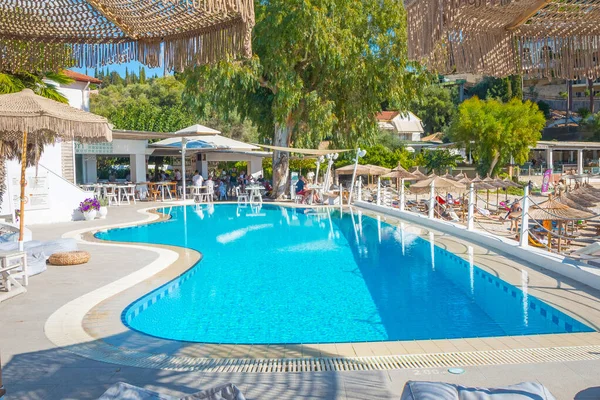 Korfu, Yunanistan - 30 Eylül 2019: Güneşli yaz gününde deniz ve kıyı manzaralı yüzme havuzu manzarası ve güneşli yataklar, Korfu, Yunanistan