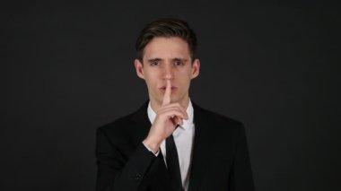 Sessizlik, koyu siyah arka plan, parmak dudaklarında