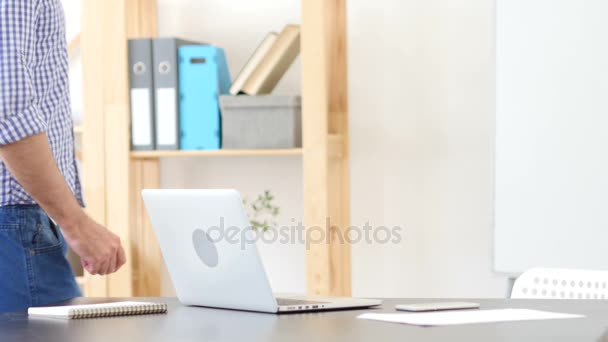 Homem chegando ao trabalho, começa a trabalhar no laptop — Vídeo de Stock