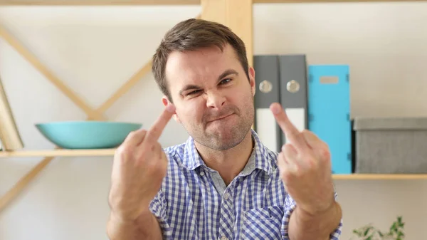 Mann zeigt Mittelfinger, sitzt im Büro — Stockfoto