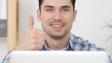 Başparmak yukarıya dizüstü bilgisayarda çalışan adam tarafından