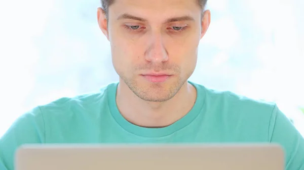 Młody człowiek pracy na laptopie w biurze, widok z przodu z bliska — Zdjęcie stockowe