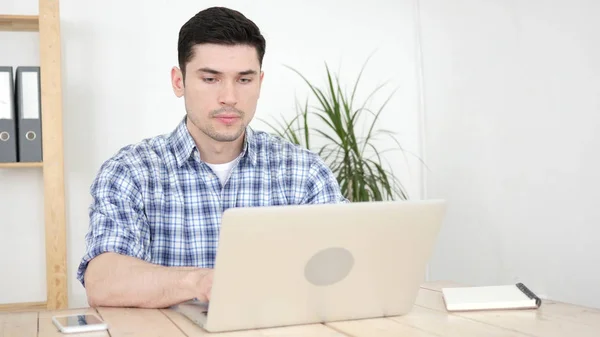 Poważny człowiek, wpisując na laptopie w biurze — Zdjęcie stockowe