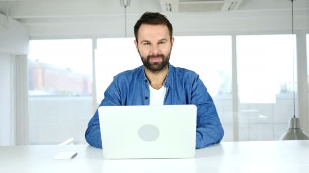 Daumen hoch von einem Mann, der im Büro sitzt und in die Kamera schaut — Stockvideo