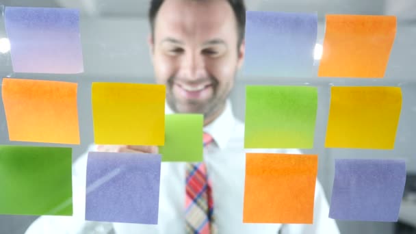 Zakenman bezig met kleverige nota's aangesloten op glas in Office — Stockvideo