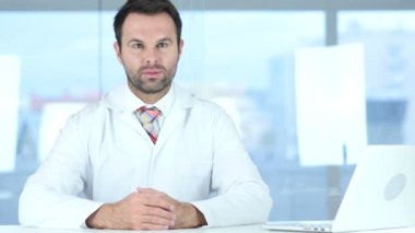 Klinikte oturmuş kamera bakarak doktor portresi