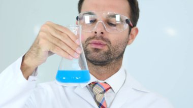 Şişeye laboratuvar mavi çözümde bakarak ciddi bilim adamı
