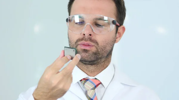 Uomo in occhiali protettivi guardando il chip del computer — Foto Stock