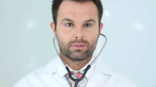 Lekarz siedzi w klinice sobie stetoskop w uszach — Zdjęcie stockowe