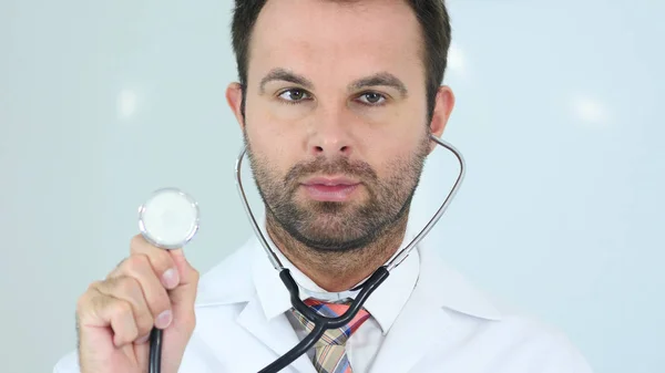 Läkare sitter i klinik med stetoskop i öron — Stockfoto