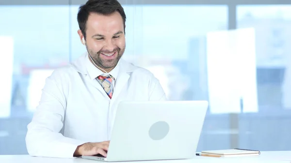 Médico sonriente trabajando en línea en el ordenador portátil en el hospital — Foto de Stock