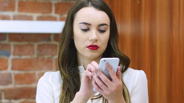 Молодая женщина с помощью смартфона на работе, красные губы — стоковое видео