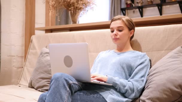 Mujer emocionada celebrando el éxito mientras trabaja en el ordenador portátil, sentado en el sofá — Vídeos de Stock