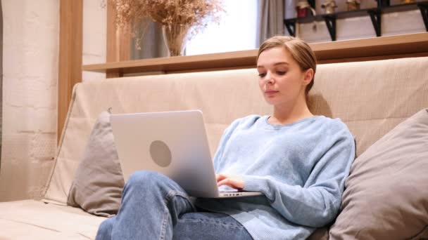 Donna che lavora sul computer portatile mentre si siede sul divano a casa — Video Stock