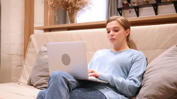 Scioccato, Wondering Woman che lavora sul computer portatile, seduto sul divano a casa — Video Stock