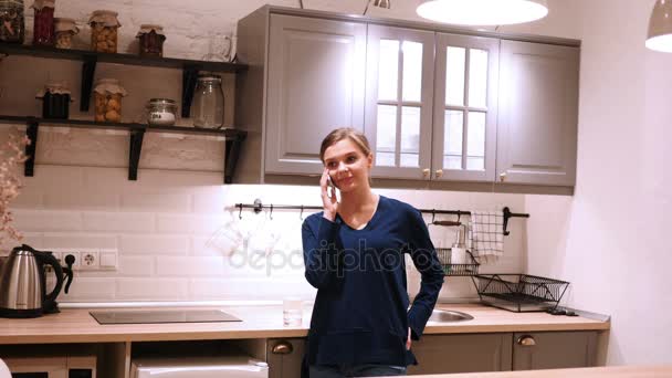 Mulher à noite falando ao telefone na cozinha, respondendo chamada — Vídeo de Stock