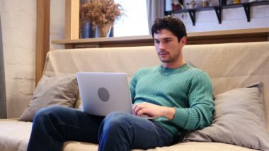 Adam kanepede oturan Laptop üzerinde çalışırken başarı kutluyor