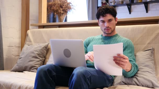 Formalności na laptopa i dokumenty przez mężczyzna siedzi na kanapie w domu — Wideo stockowe