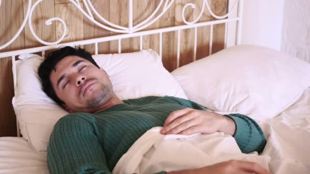 Zor bir gün yaptıktan sonra yatakta uyuyan rahatlatıcı genç adam — Stok video