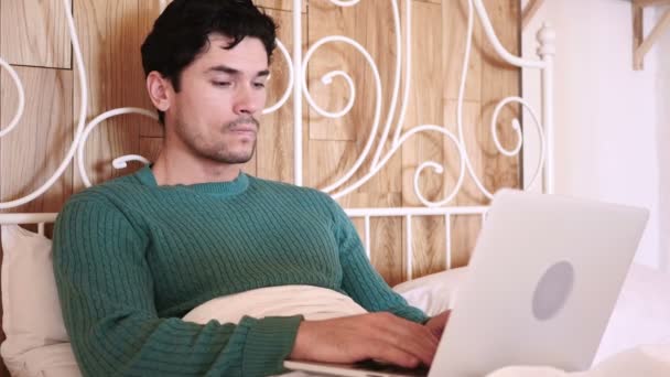 Homem sentado na cama trabalhando no laptop — Vídeo de Stock