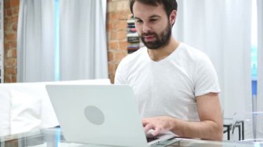 Heyecanlı sakallı adam kutluyor Laptop, kanepede oturan üzerinde çalışırken başarı