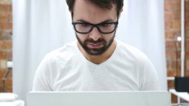 Dizüstü bilgisayarda çalışan sinirli sinirli sakallı adam