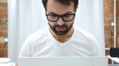 Dizüstü bilgisayarda çalışan ciddi genç sakallı adam portresi