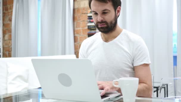 Retrato del hombre barba bebiendo café de la taza y trabajando en el ordenador portátil — Vídeo de stock