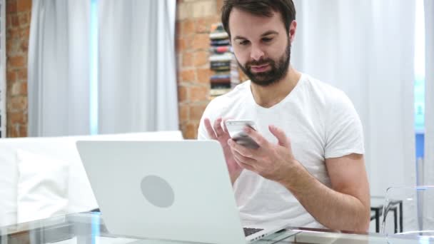 Barba hombre hojeando en línea en el teléfono inteligente, escribiendo mensaje — Vídeo de stock