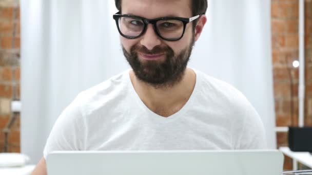 Sacudiendo la cabeza a No, joven barba trabajando en el ordenador portátil en casa — Vídeo de stock