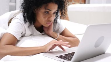 Baş ağrısı, sinir bozucu Afro-Amerikan kadın yatakta laptop çalışma