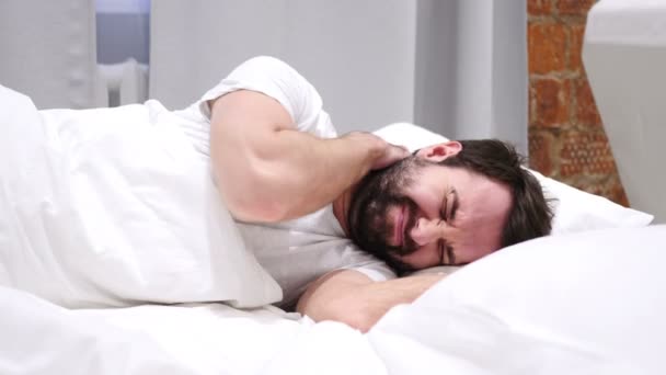 Бородач с болью в шее пытается расслабиться в постели — стоковое видео