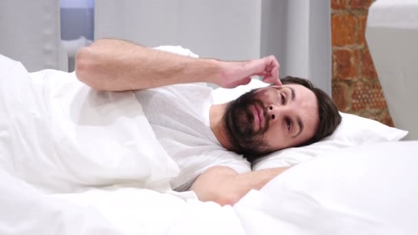 Tänkande, fundersam Man liggande på sidan och drömmer medan i sängen — Stockvideo