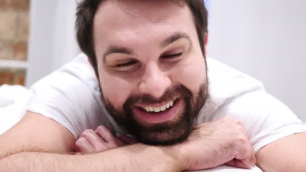 Primer plano de la cara sonriente del hombre de la barba acostado en la cama — Vídeos de Stock