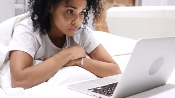 Üzgün Afro-Amerikan kadın yatakta dizüstü bilgisayarda çalışan ve kaybı için tepki — Stok video