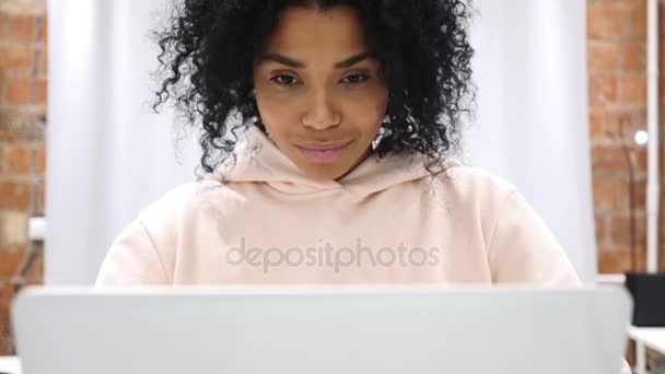 Retrato de una mujer afro-americana sonriente y positiva trabajando en un ordenador portátil — Vídeo de stock
