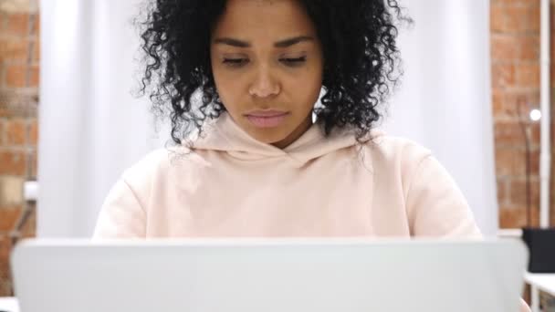 Retrato de una mujer afro-americana sonriente y positiva trabajando en un ordenador portátil — Vídeo de stock