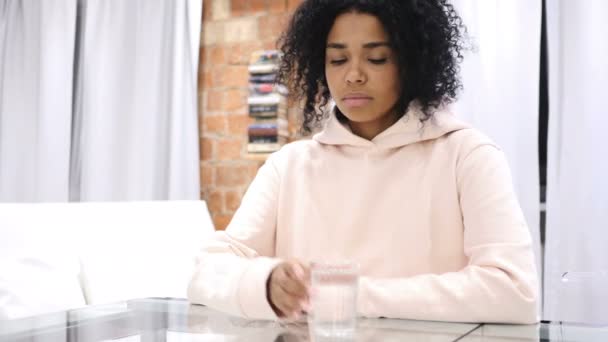 Retrato de una mujer afroamericana bebiendo agua de un vaso y trabajando en un ordenador portátil — Vídeo de stock