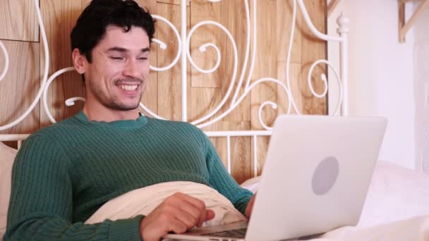 男がベッドで横になっているノート パソコンでオンライン ビデオ チャット リラックス — ストック動画