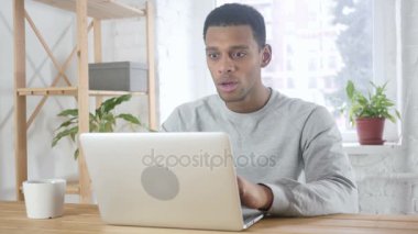 Heyecanlı Afro-Amerikan adam kutluyor Laptop, kanepede oturan üzerinde çalışırken başarı