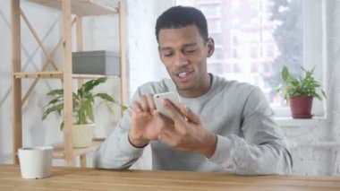 Heyecanlı Afro-Amerikan adam kutluyor başarı Smartphone kullanarak süre